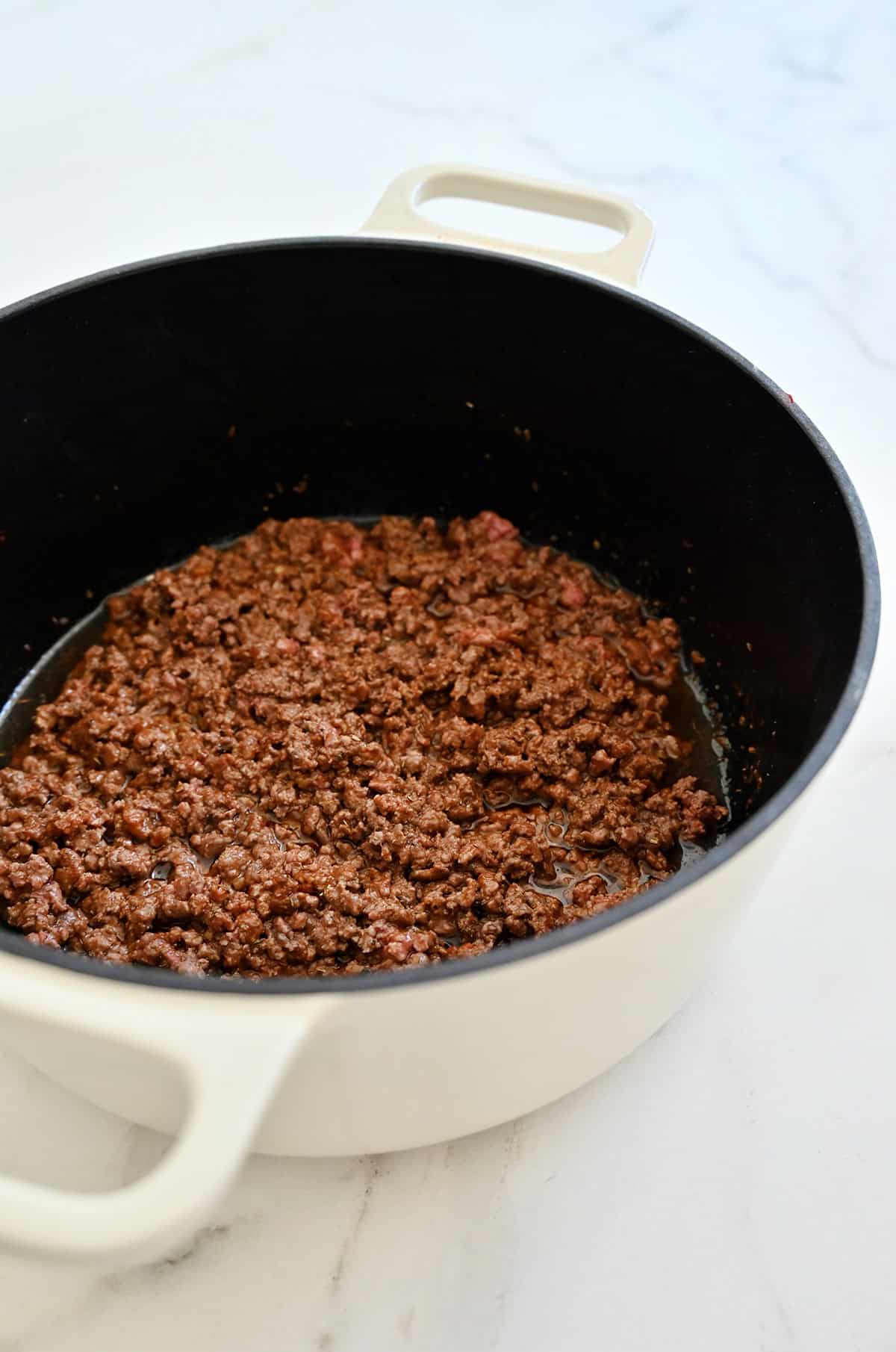 Finely crumbled cooked ground beef for bolognese in a large pot.