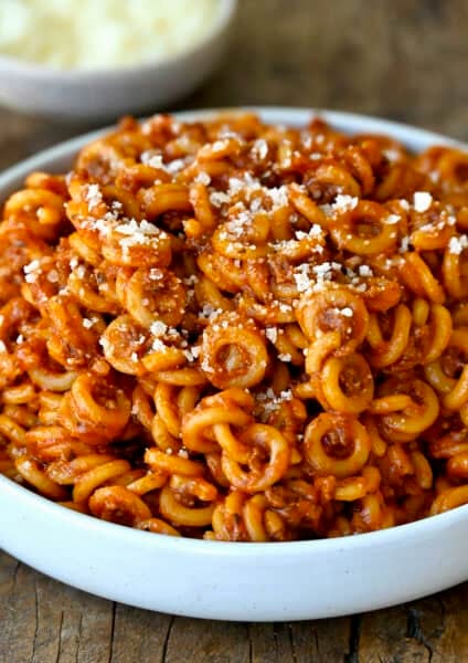 Homemade SpaghettiOs in a dinner bowl topped with grated parmesan cheese.