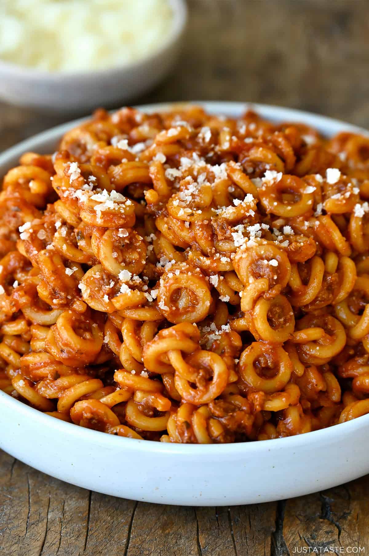 Homemade SpaghettiOs in a dinner bowl topped with grated parmesan cheese.