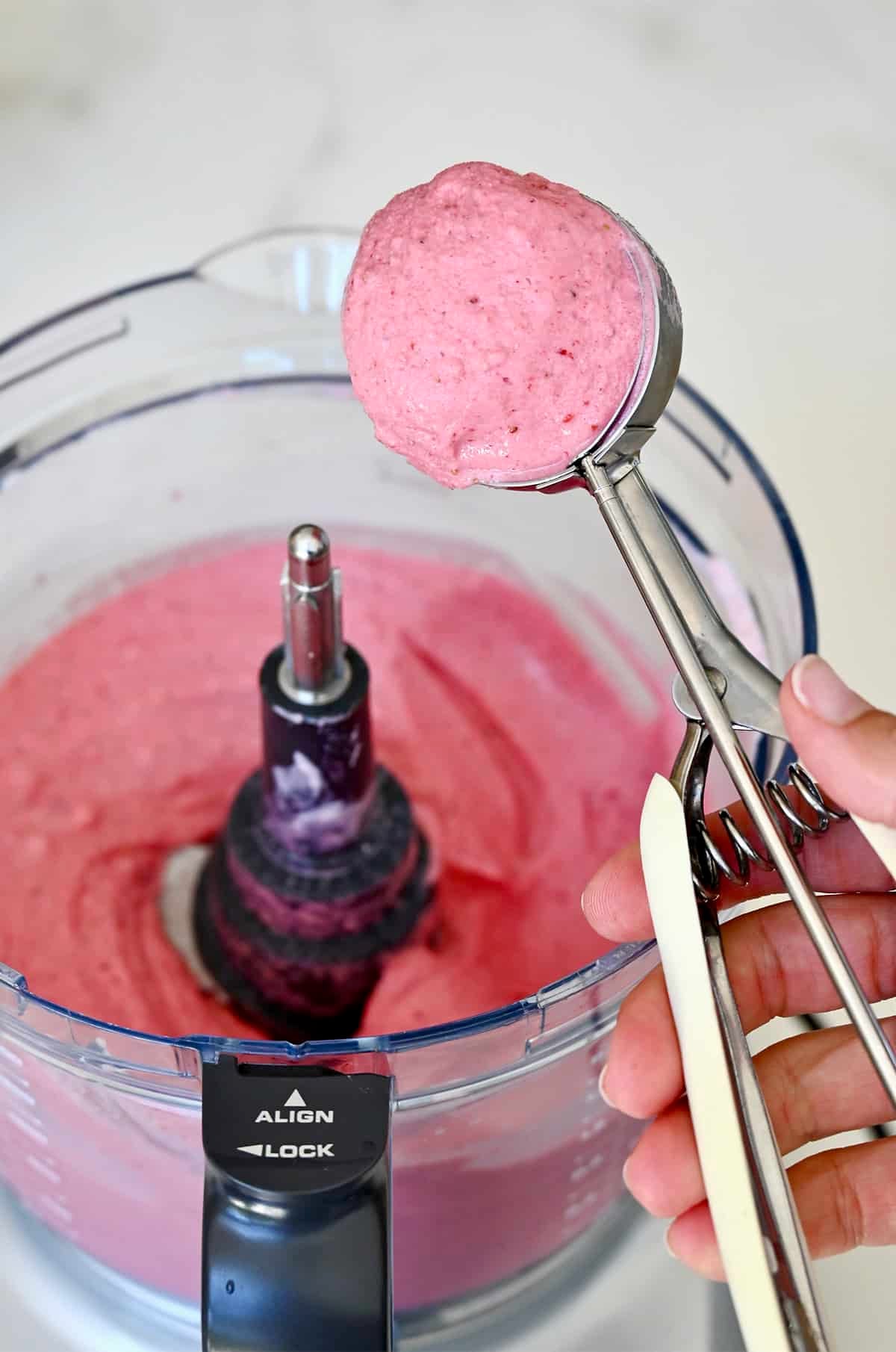 An ice cream scoop with cottage cheese ice cream.