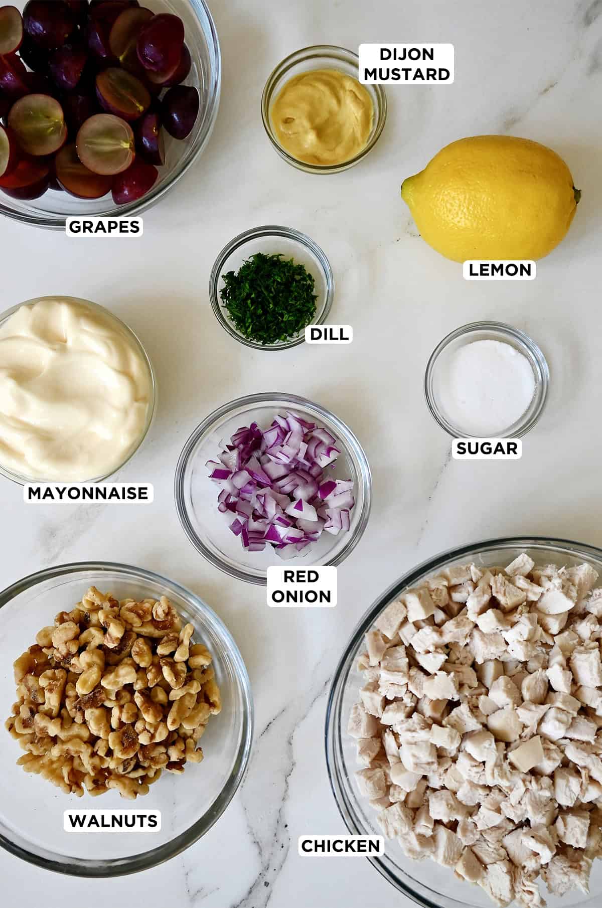Chicken salad ingredients in various sizes of glass mixing bowls.