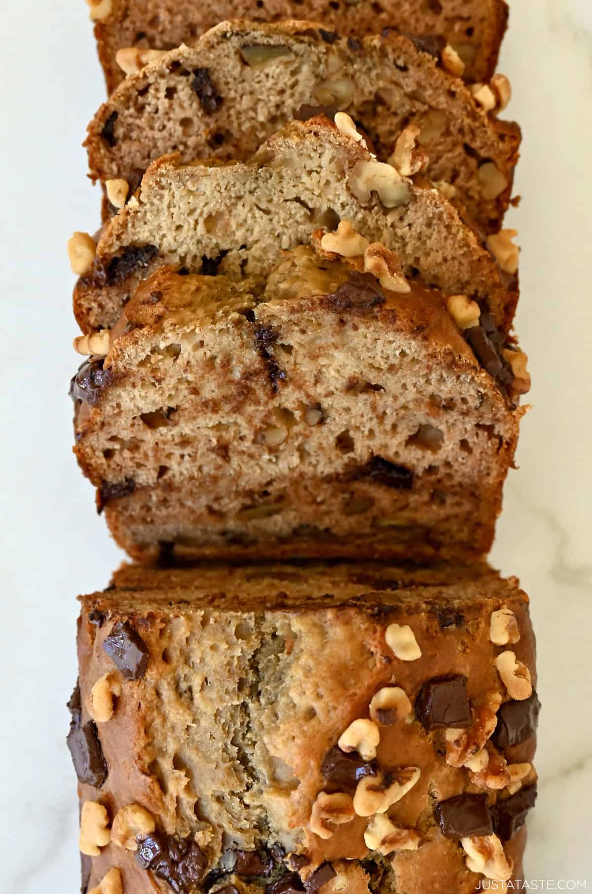 A loaf of golden brown banana bread made with cottage cheese and studded with chocolate chips and walnuts.