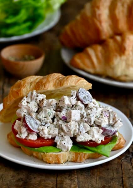 Chicken salad with grapes and walnuts on a croissant with lettuce and tomato.