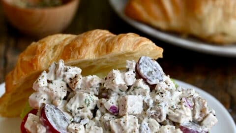Chicken salad with grapes and walnuts on a croissant with lettuce and tomato.
