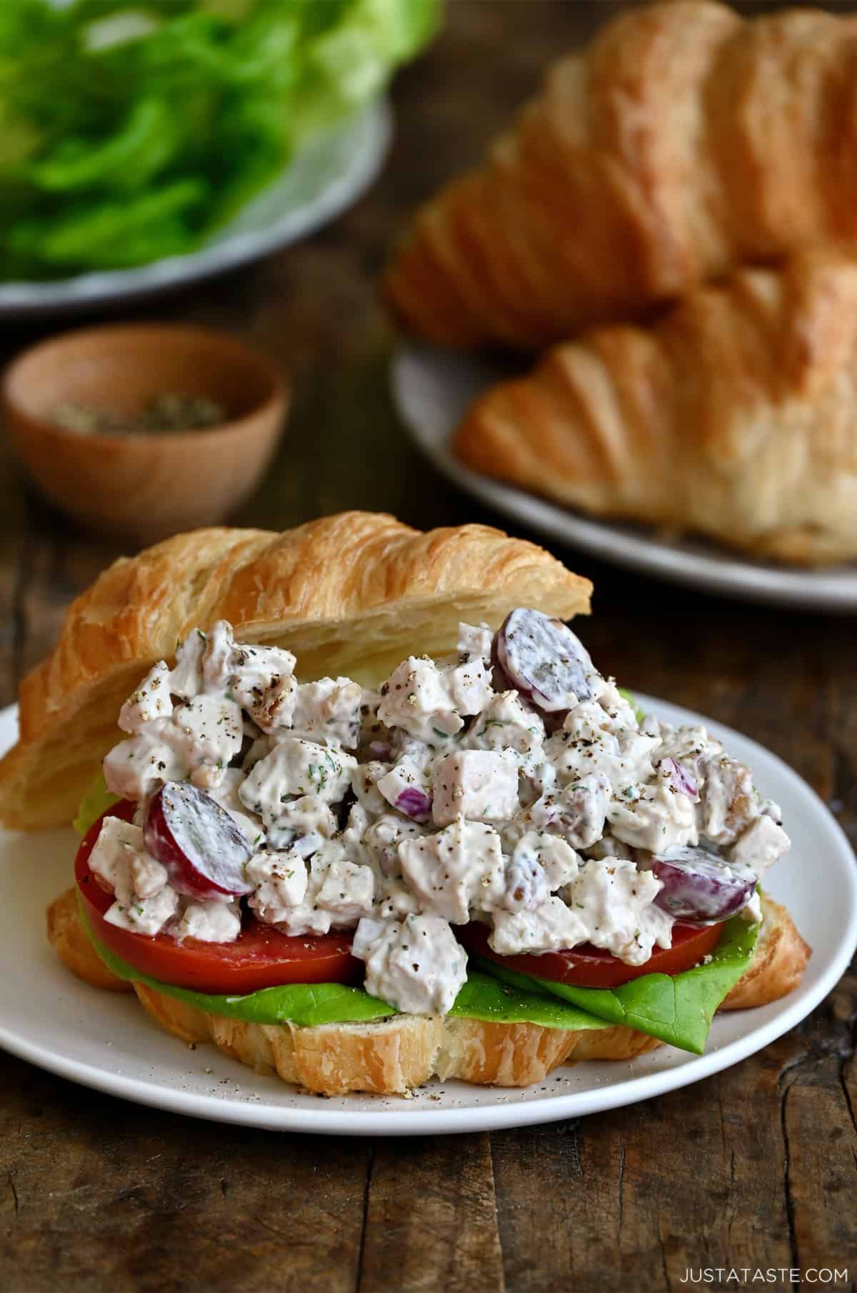 Chicken salad with grapes and walnuts on a croissant with lettuce and tomato.