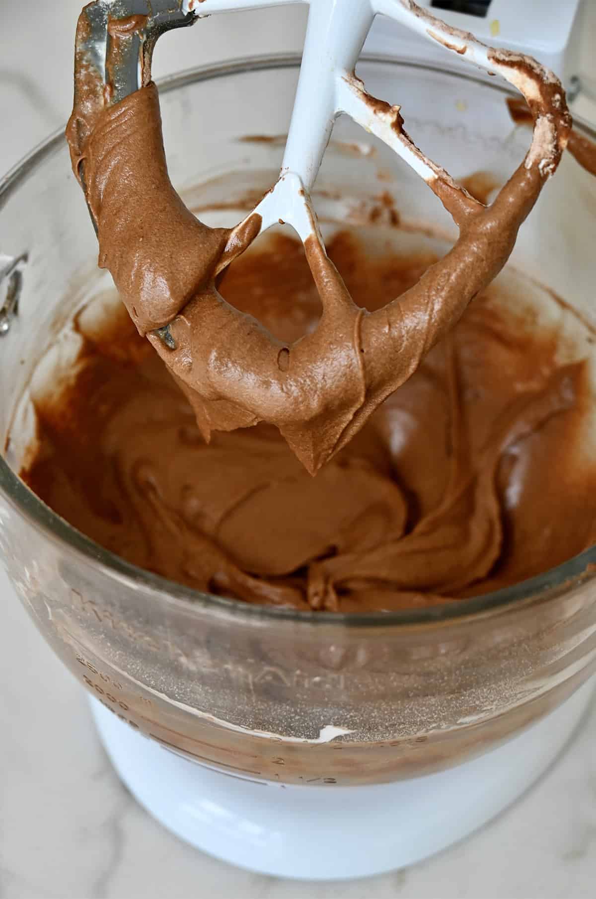 Chocolate cake batter in the bowl of a stand mixer with the paddle attachment.