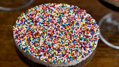 Cocktail dot cakes starring chocolate cake topped with vanilla buttercream frosting and a layer of rainbow sprinkles in a cocktail glass.