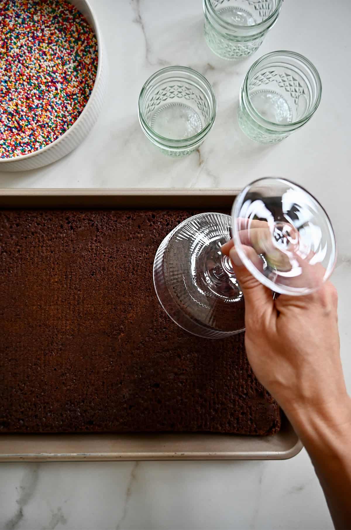 Cutting out cake on a jelly roll pan with a cocktail glass.
