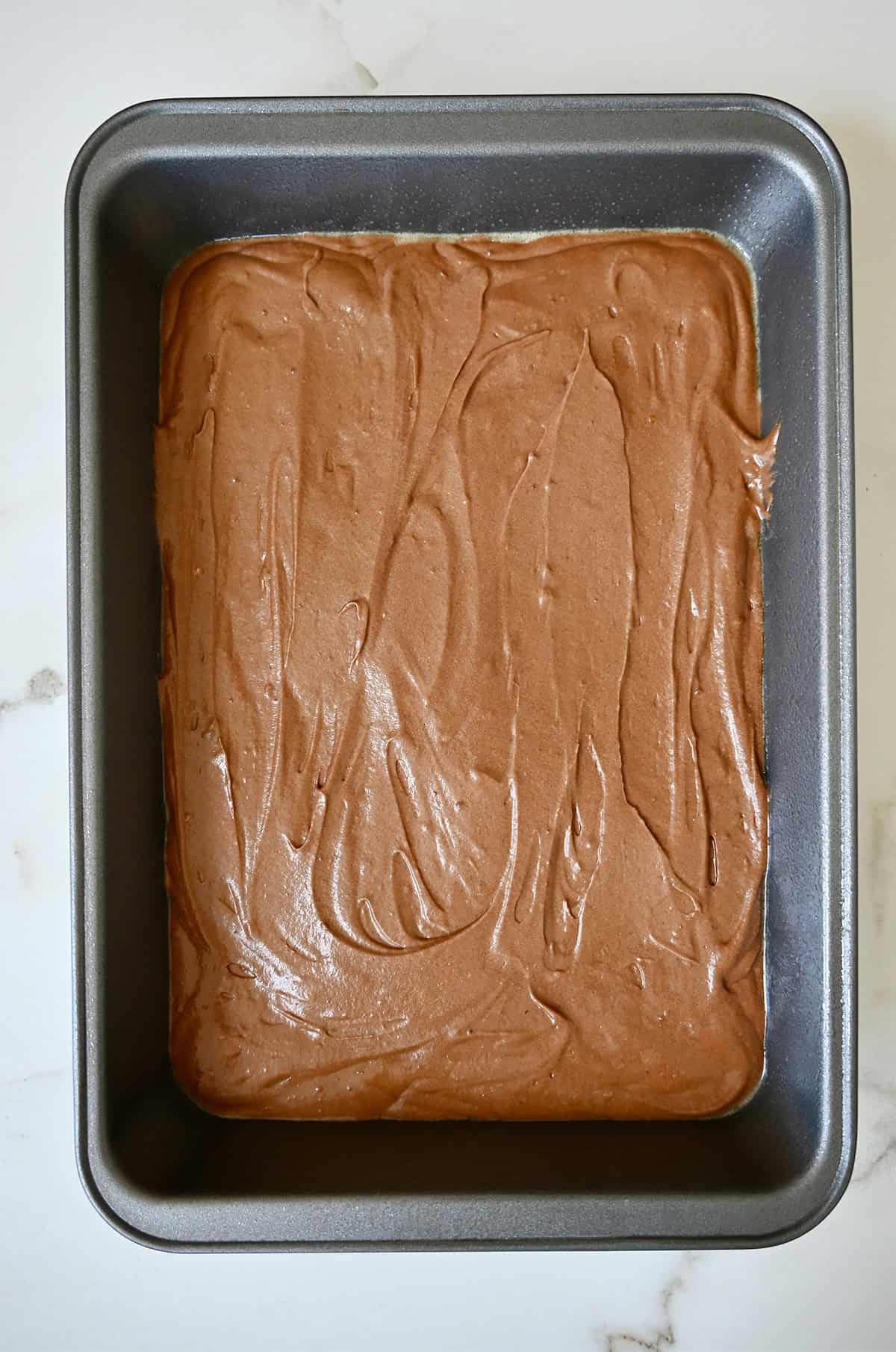 Unbaked thin chocolate cake in a 9x13 pan.