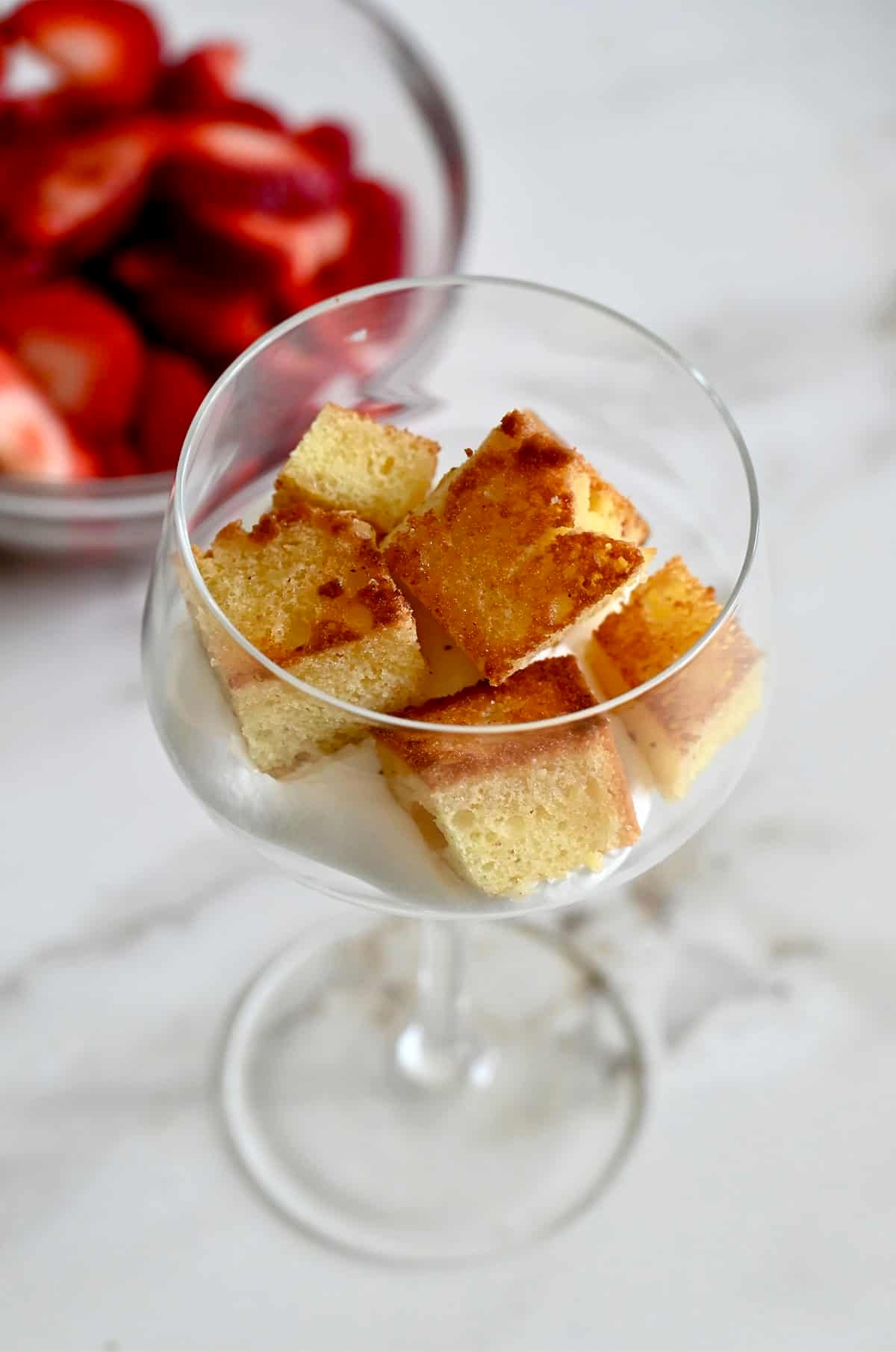 Toasted pound cake croutons atop whipped cream in a cocktail glass.