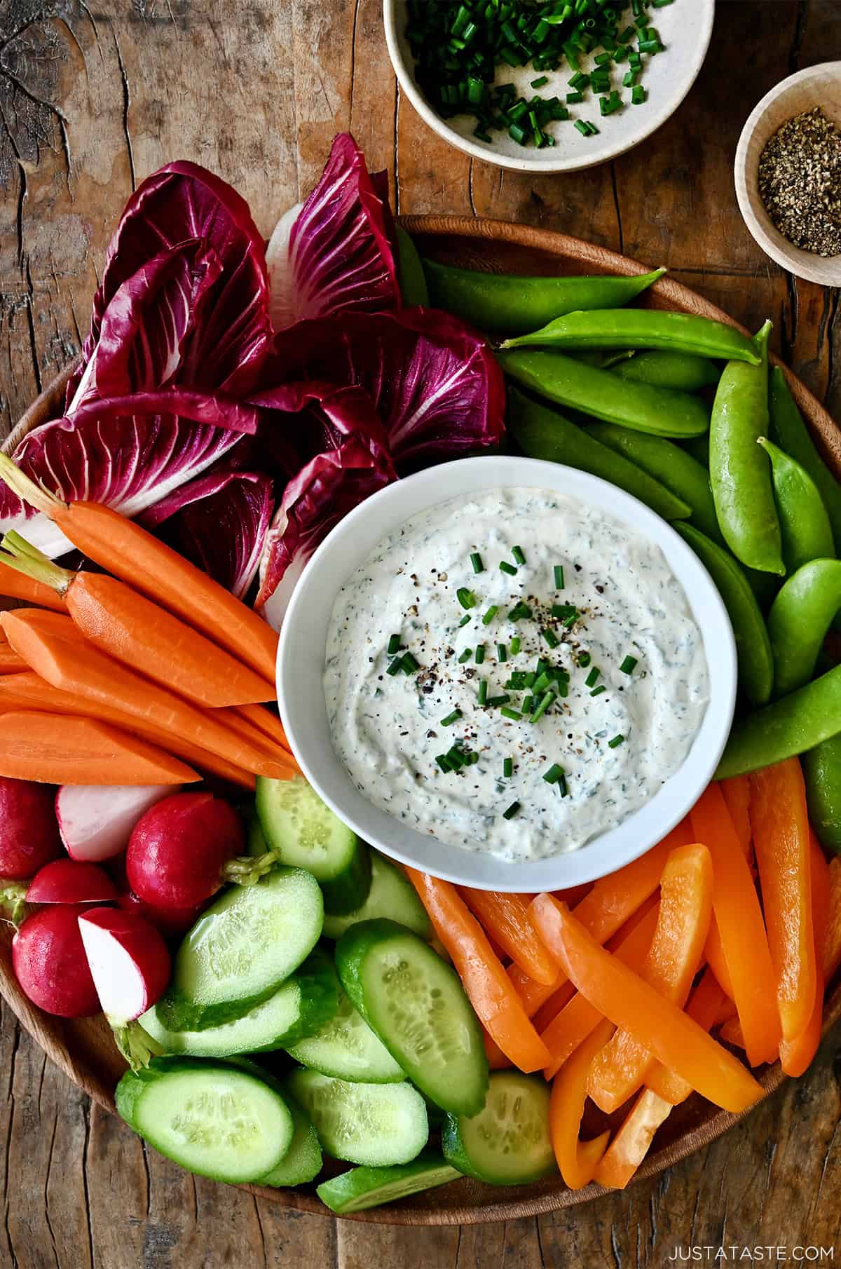 Veggie dip in a small bowl on a serving platter surrounded by fresh veggies.