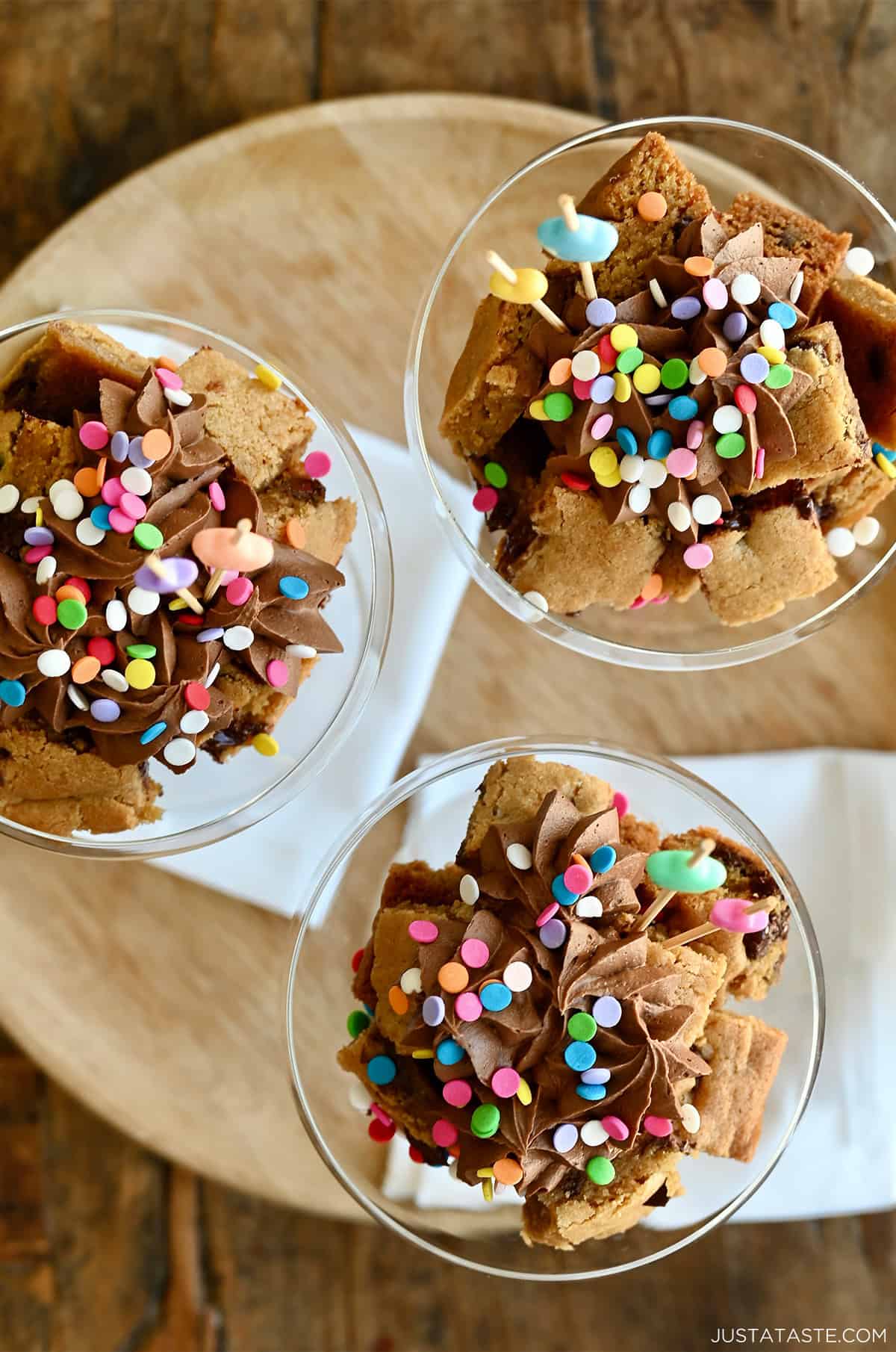Cookie cake cut into cubes, layered in a martini glass with chocolate buttercream frosting and sprinkles.