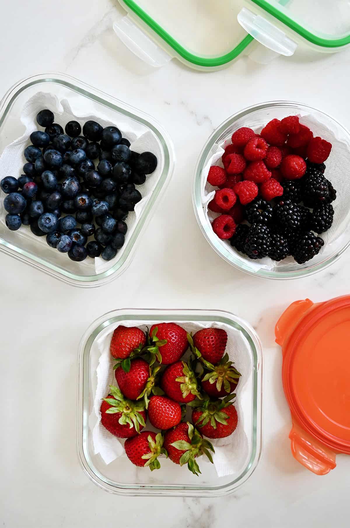 Fresh berries in glass containers lined with paper towels.