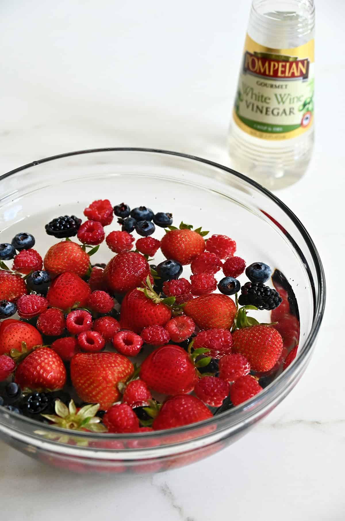 Soaking fresh strawberries, blueberries, and raspberries in a mixture of water and vinegar.
