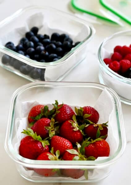Storing fresh berries in glass containers lined with paper towels and sealed with airtight lids.