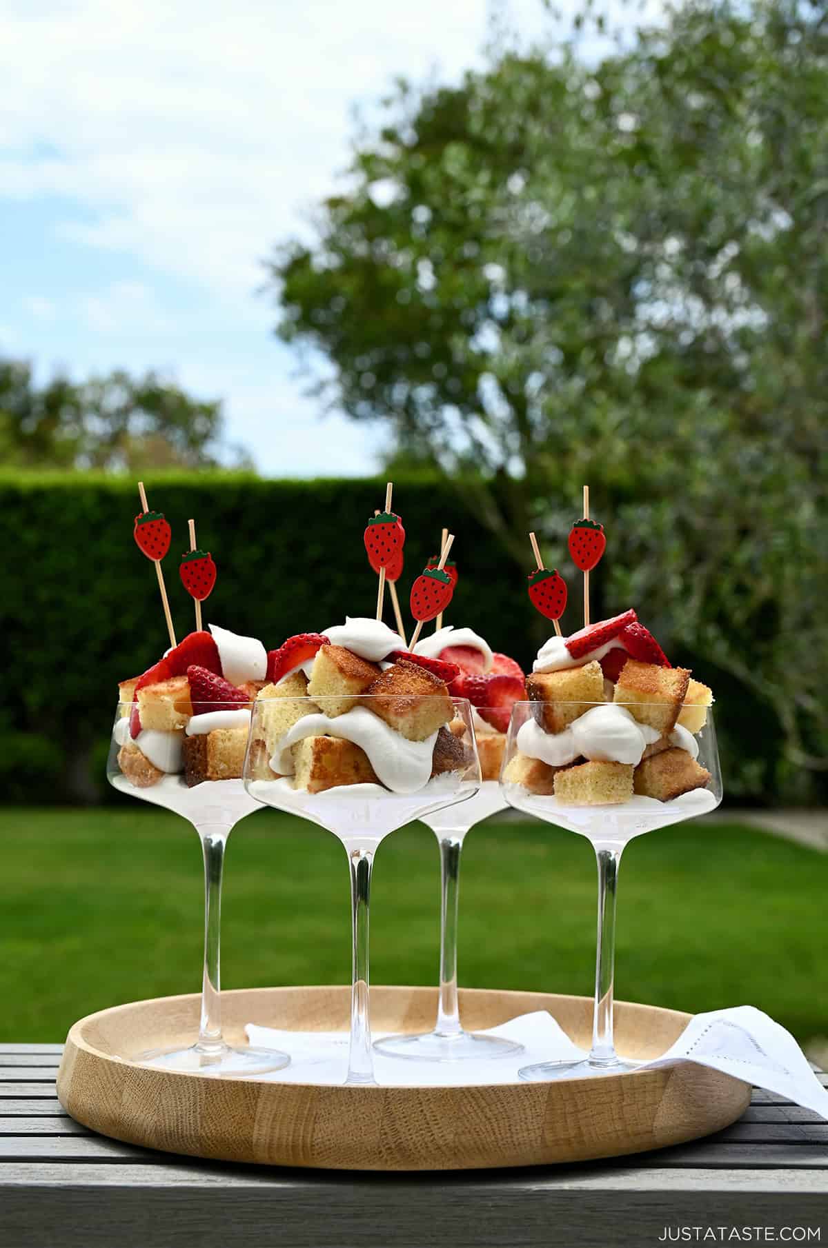 Strawberries and cream cocktail cakes on a serving tray with napkins on an outdoor table.