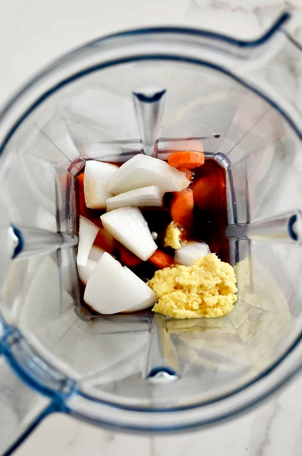 All the ingredients to make carrot-ginger dressing in a blender.
