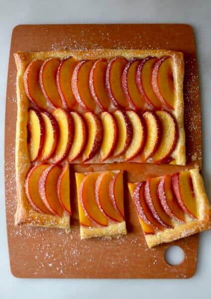 Fresh peach tart made with store-bought puff pastry and dusted with powdered sugar.