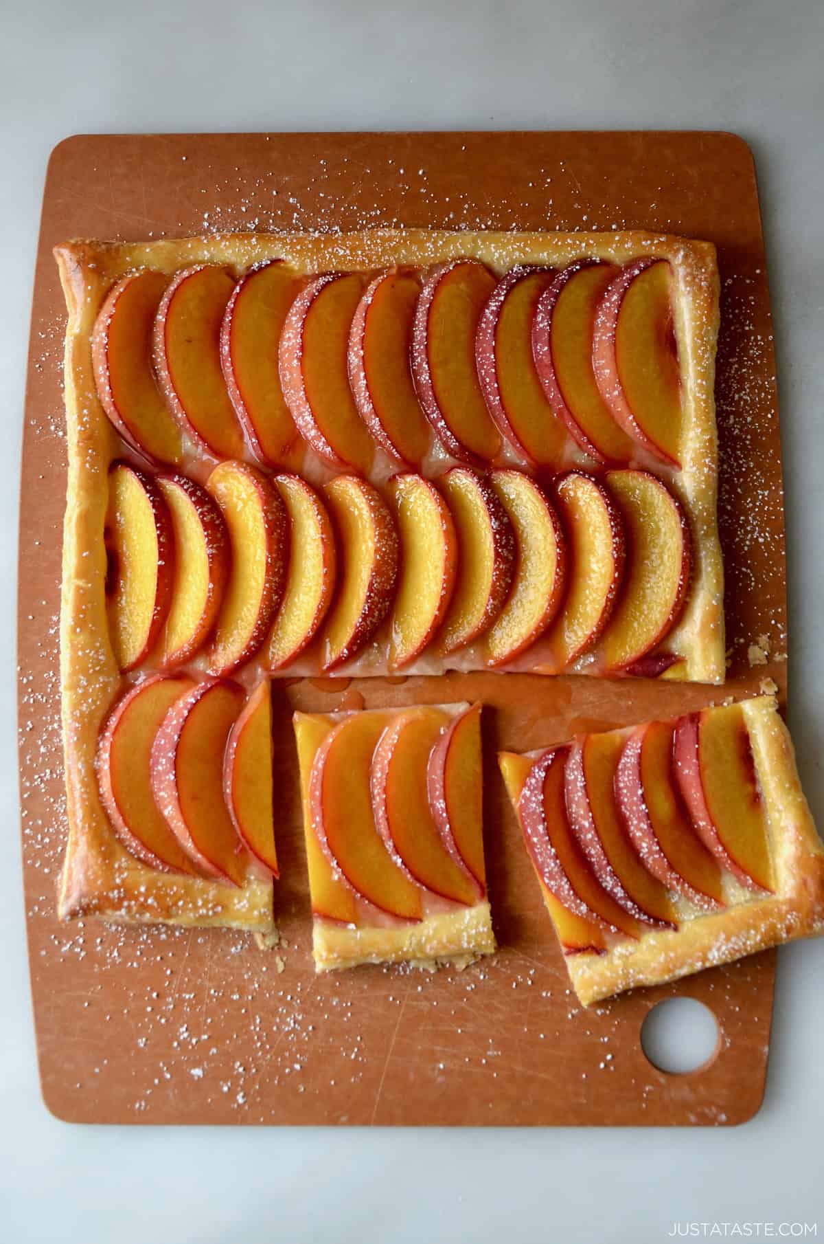 Fresh peach tart made with store-bought puff pastry and dusted with powdered sugar.