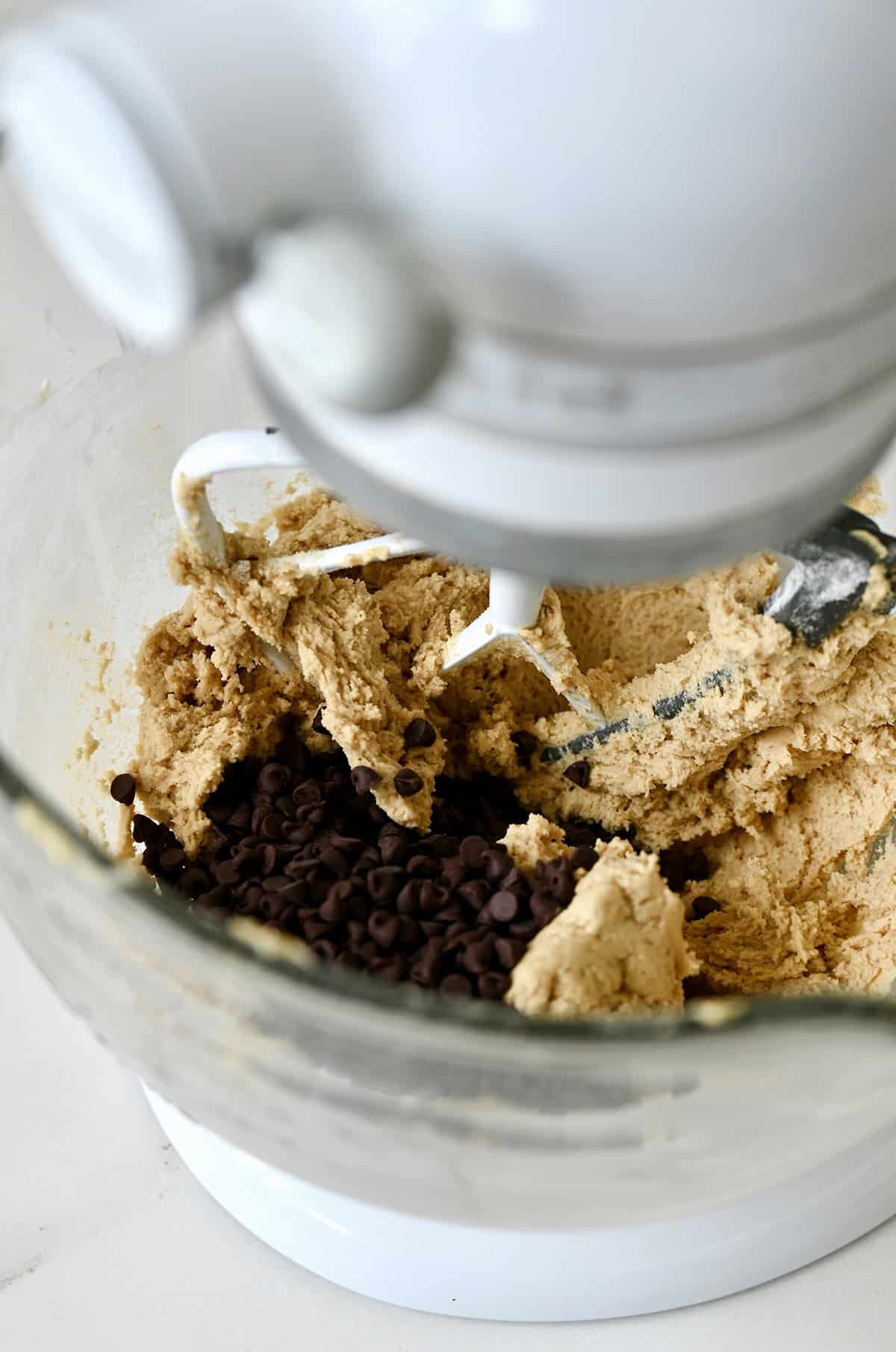 Stirring mini chocolate chips into cookie dough.