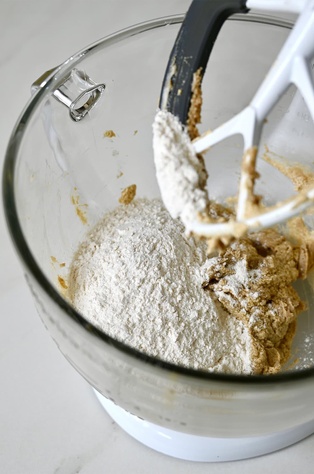 Dry ingredients being added to a stand mixer bowl to make cookie dough.