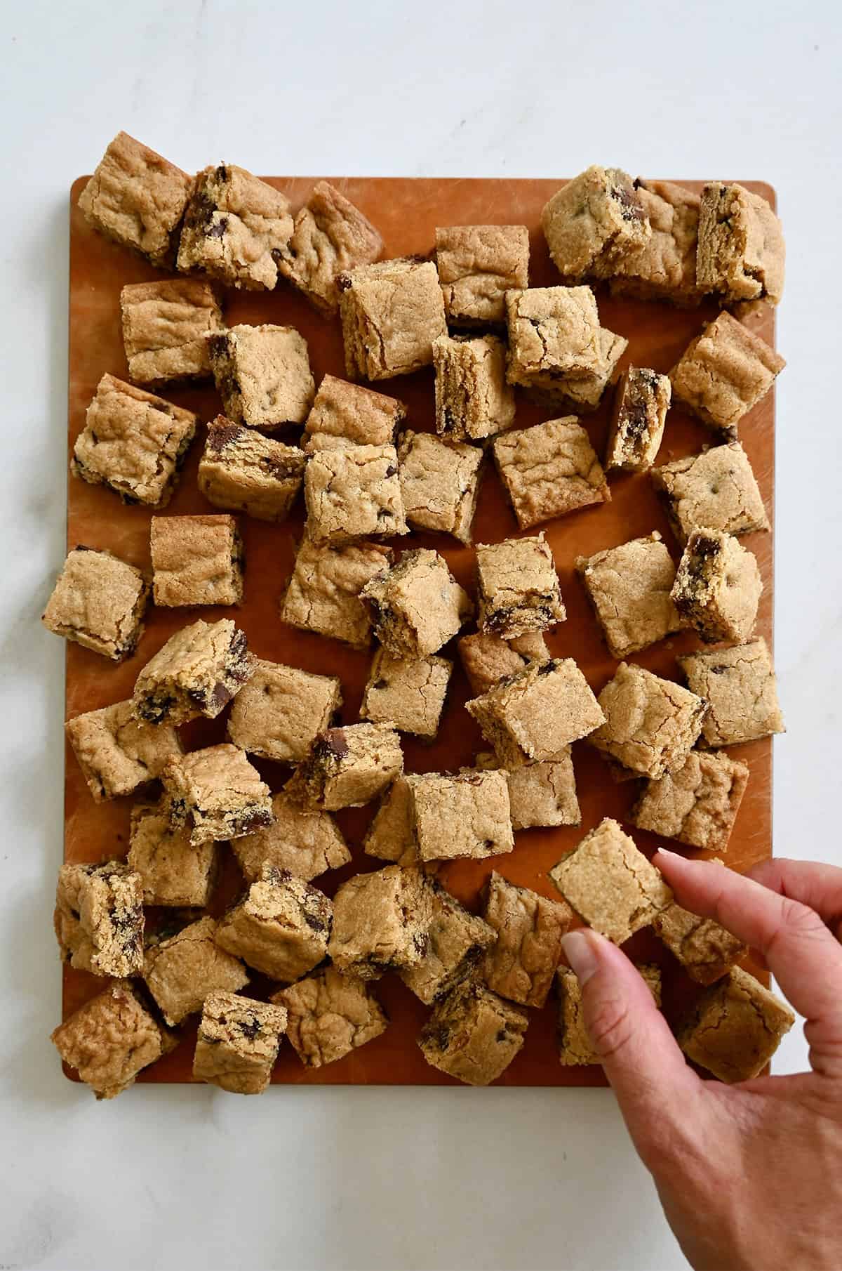 A hand holds a bite-sized soft and chewy chocolate chip cookie crouton.