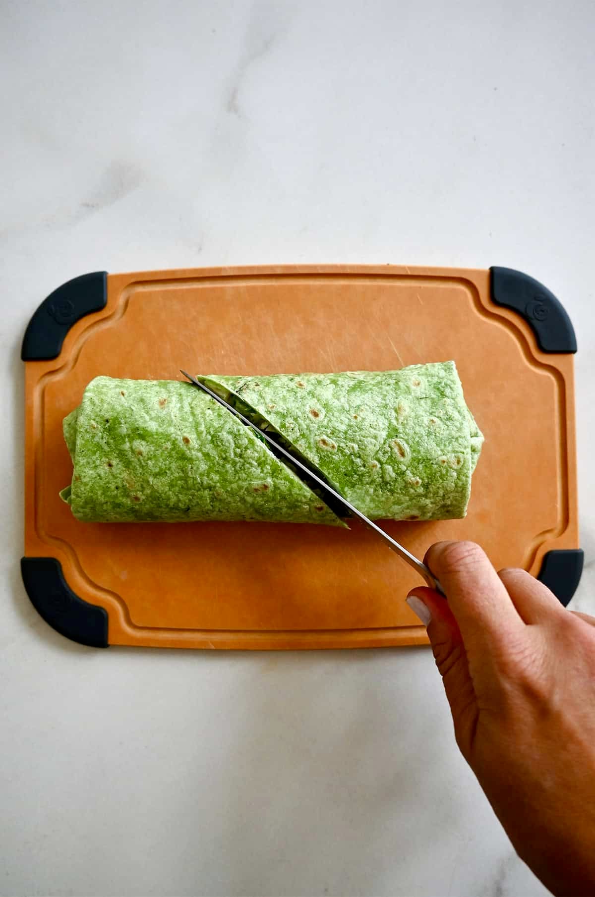 Cutting a Caesar wrap in half with a sharp knife.