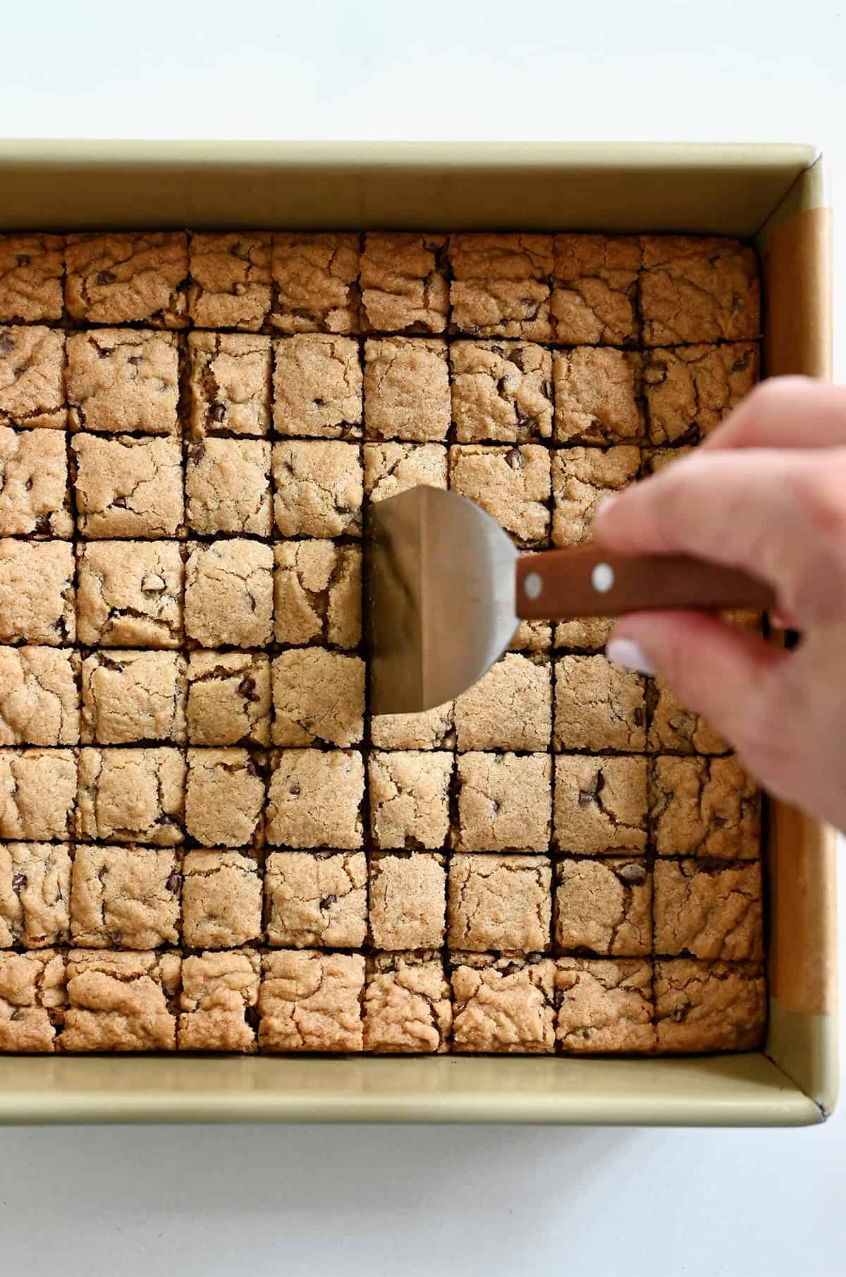 Cutting soft and chewy cookie croutons in a 9-inch square pan.
