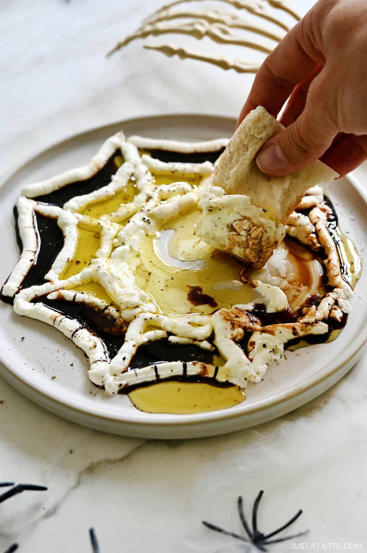 Whipped cheese piped to look like a spider's web, topped with olive oil and balsamic vinegar.