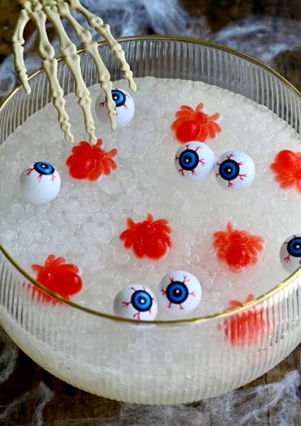 Halloween-themed punch in a punch bowl with a plastic skeleton hand reaching into it.