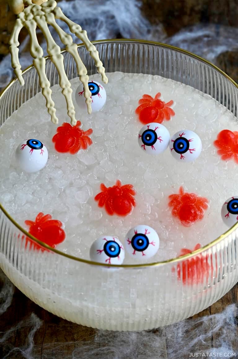 Halloween-themed punch in a punch bowl with a plastic skeleton hand reaching into it.