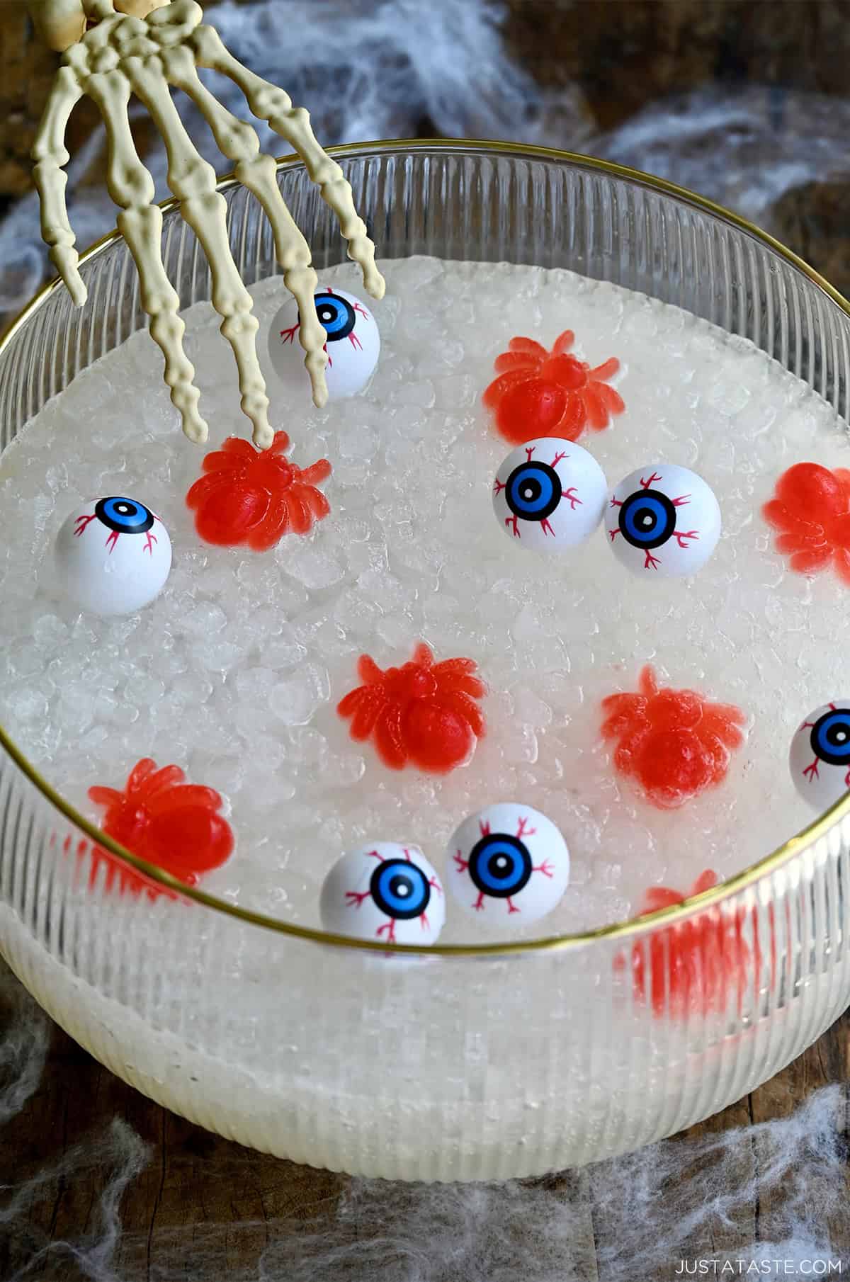 Halloween-themed punch in a punch bowl with a plastic skeleton hand reaching into it.