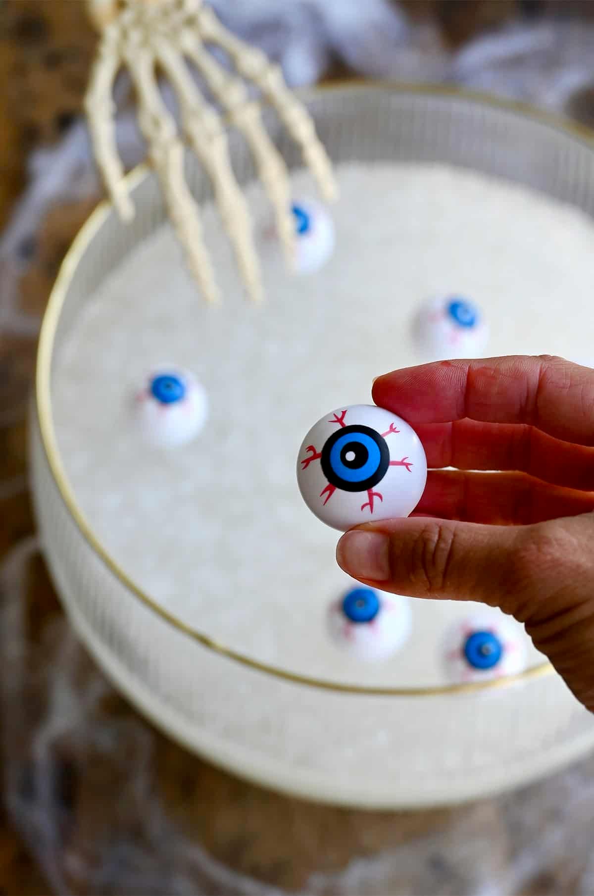 Adding bloodshot plastic eyeballs to a punch bowl containing a lemonade-vodka mixture and nugget ice.