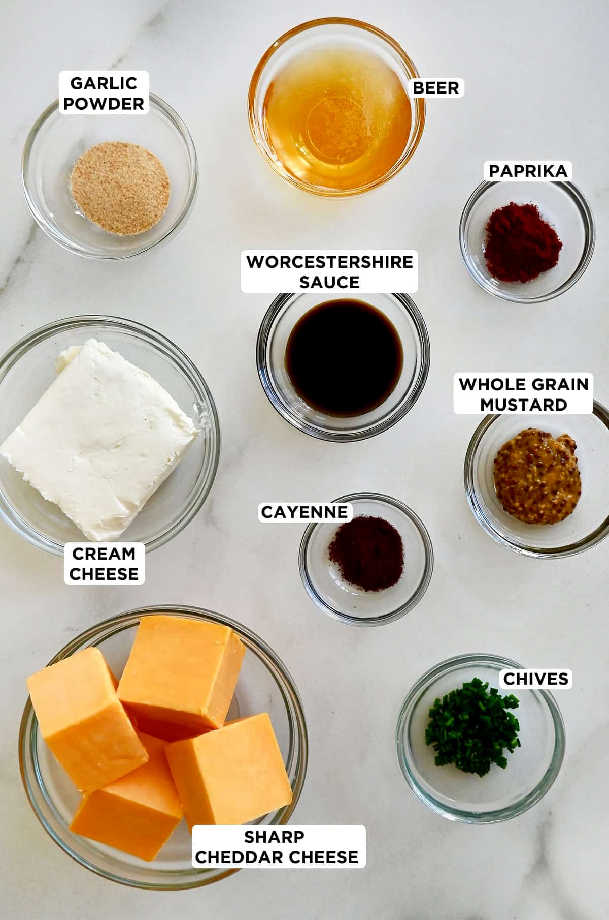 Ingredients for making pub cheese in various small glass bowls.