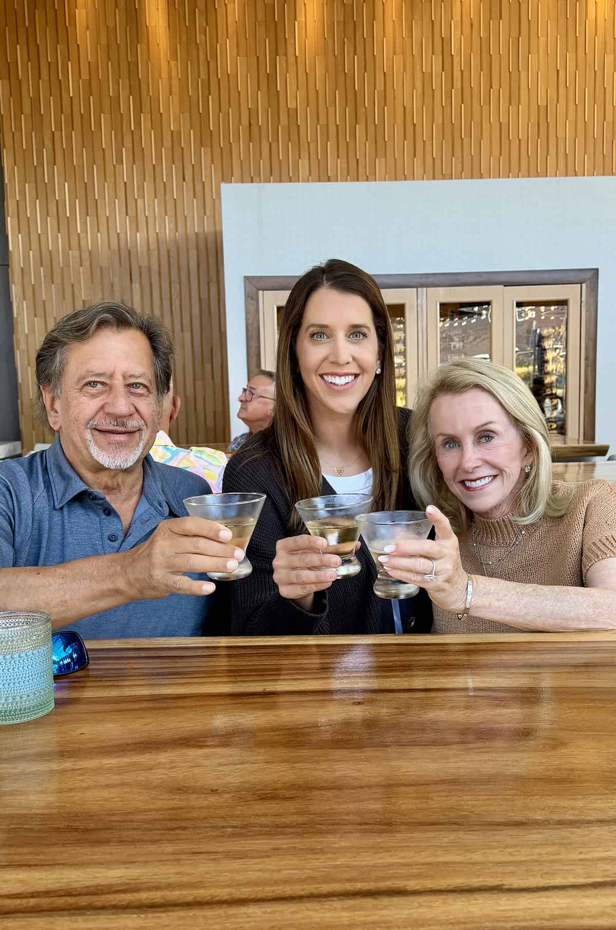 Kelly in the middle of her parents, Drew and Noni, toasting to a new work milestone.