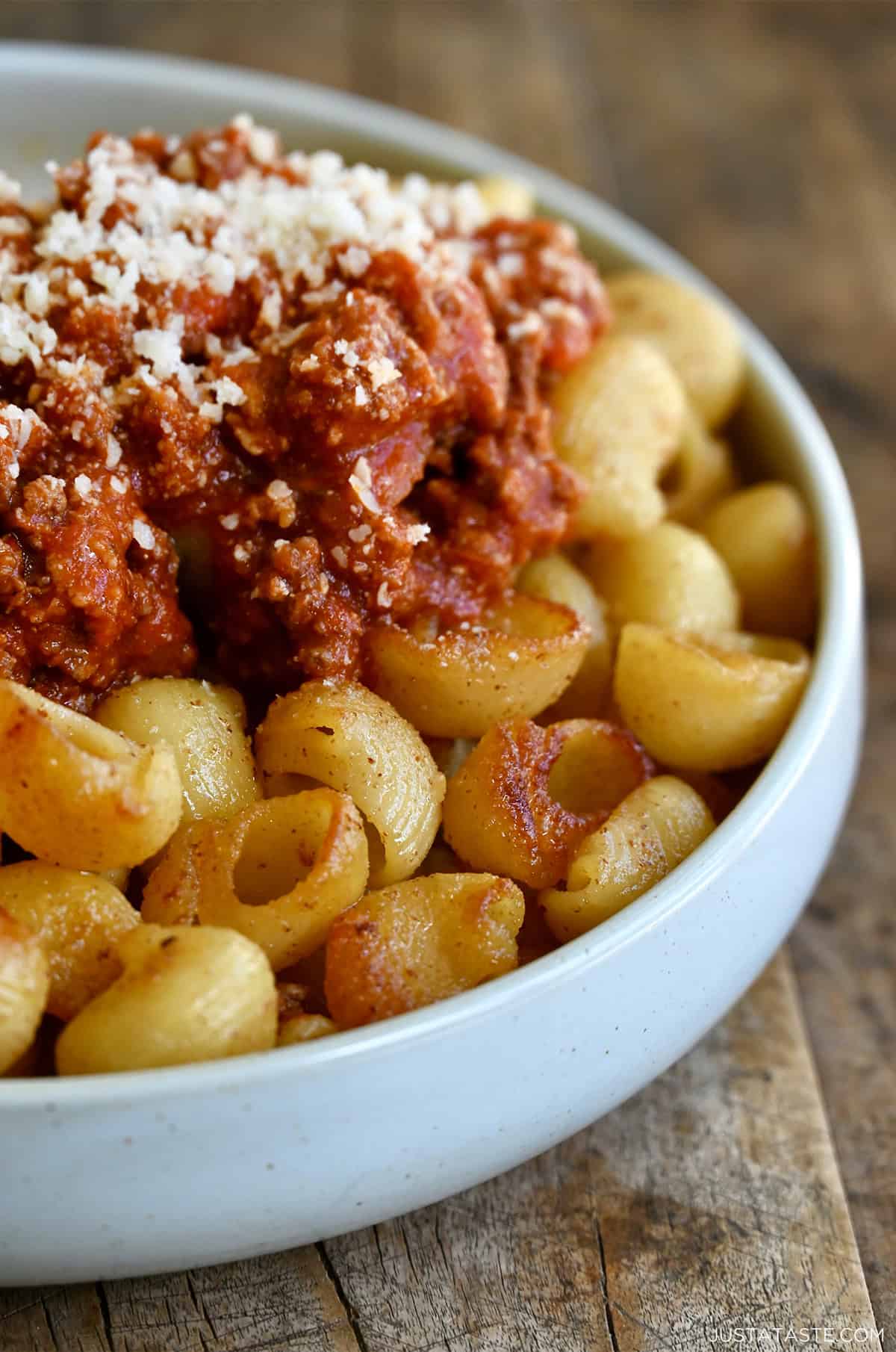 A closeup view of crispy fried spaghetti topped with spaghetti sauce in a shallow bowl.