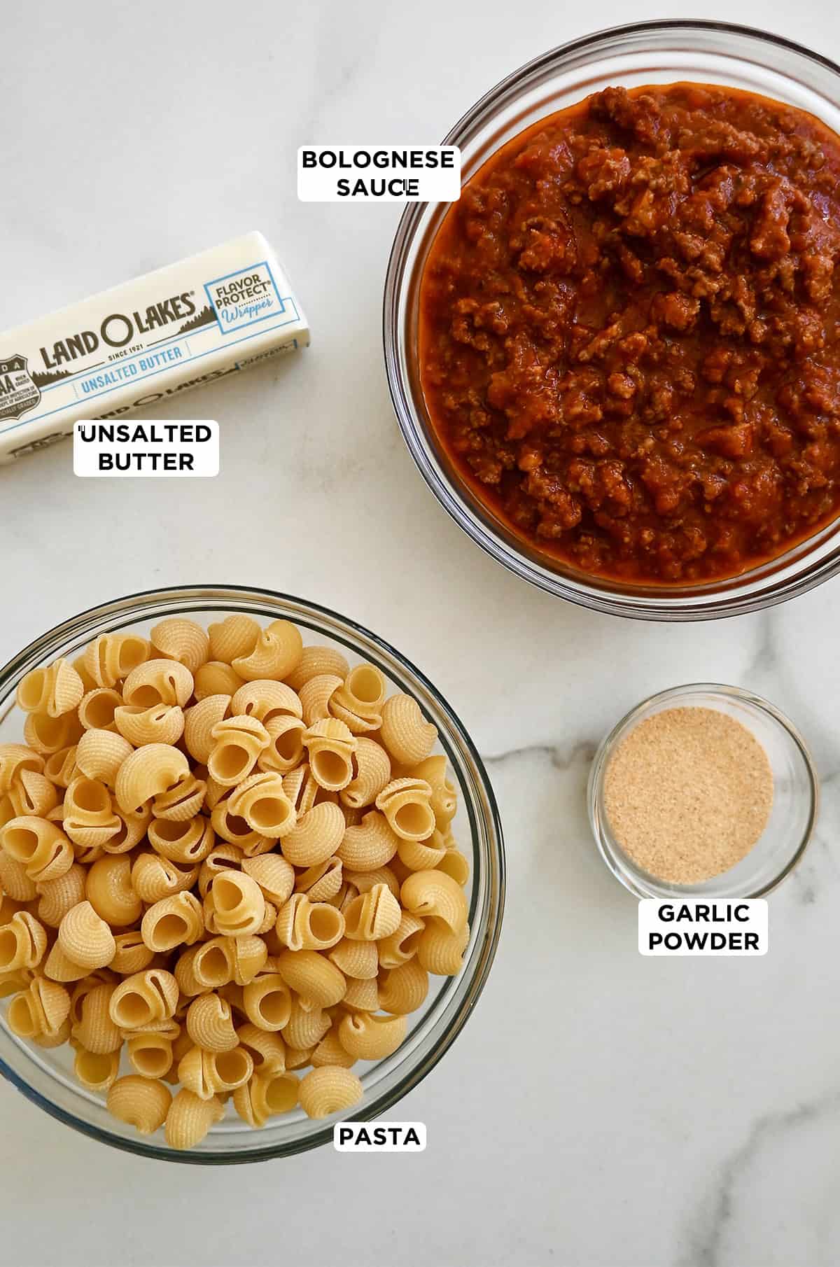 The four ingredients needed to make fried spaghetti: cooked noodles, butter, marinara sauce and garlic powder.