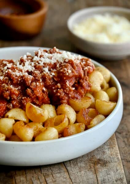 Fried spaghetti with Bolognese sauce in a shallow pasta bowl.