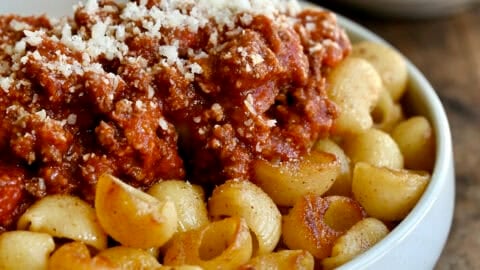 Fried spaghetti with Bolognese sauce in a shallow pasta bowl.