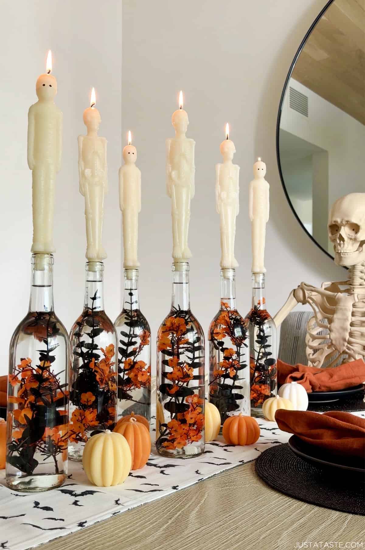 DIY Halloween wine bottle candlesticks with mummy taper candles on a Halloween themed table scape.