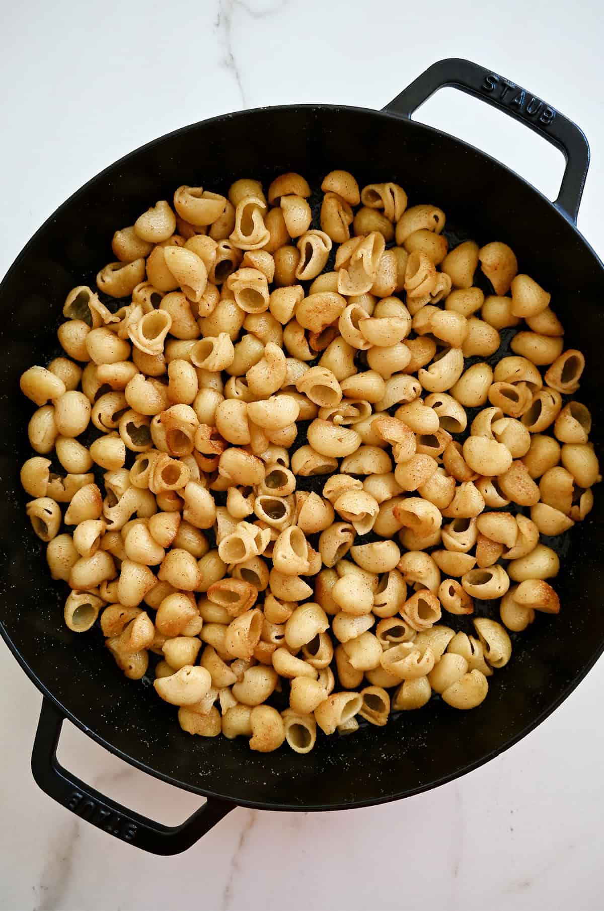 Golden brown, crispy toasted noodles with garlic butter in a large skillet.