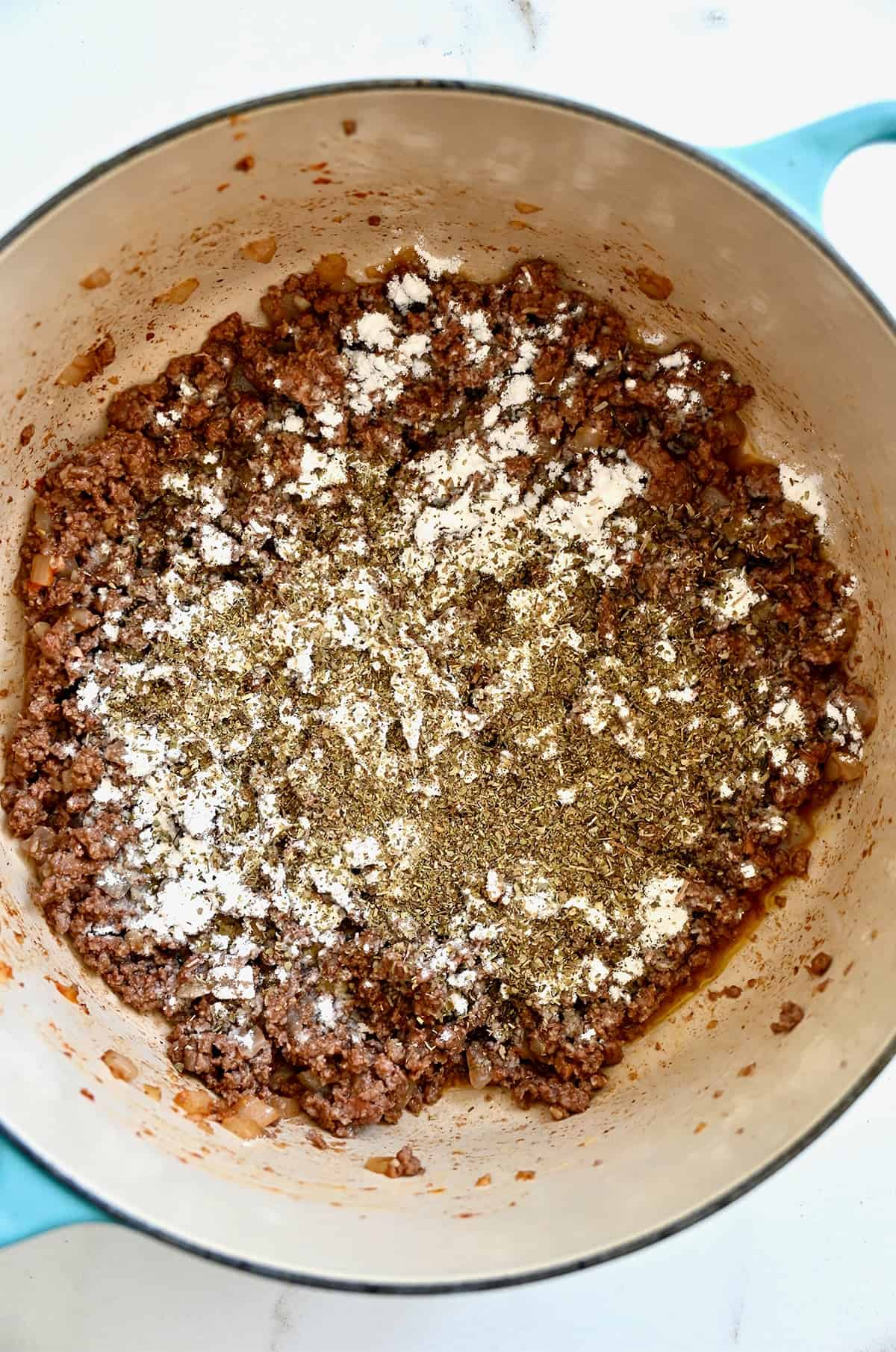 All-purpose flour and Italian seasoning sprinkled over browned ground beef.