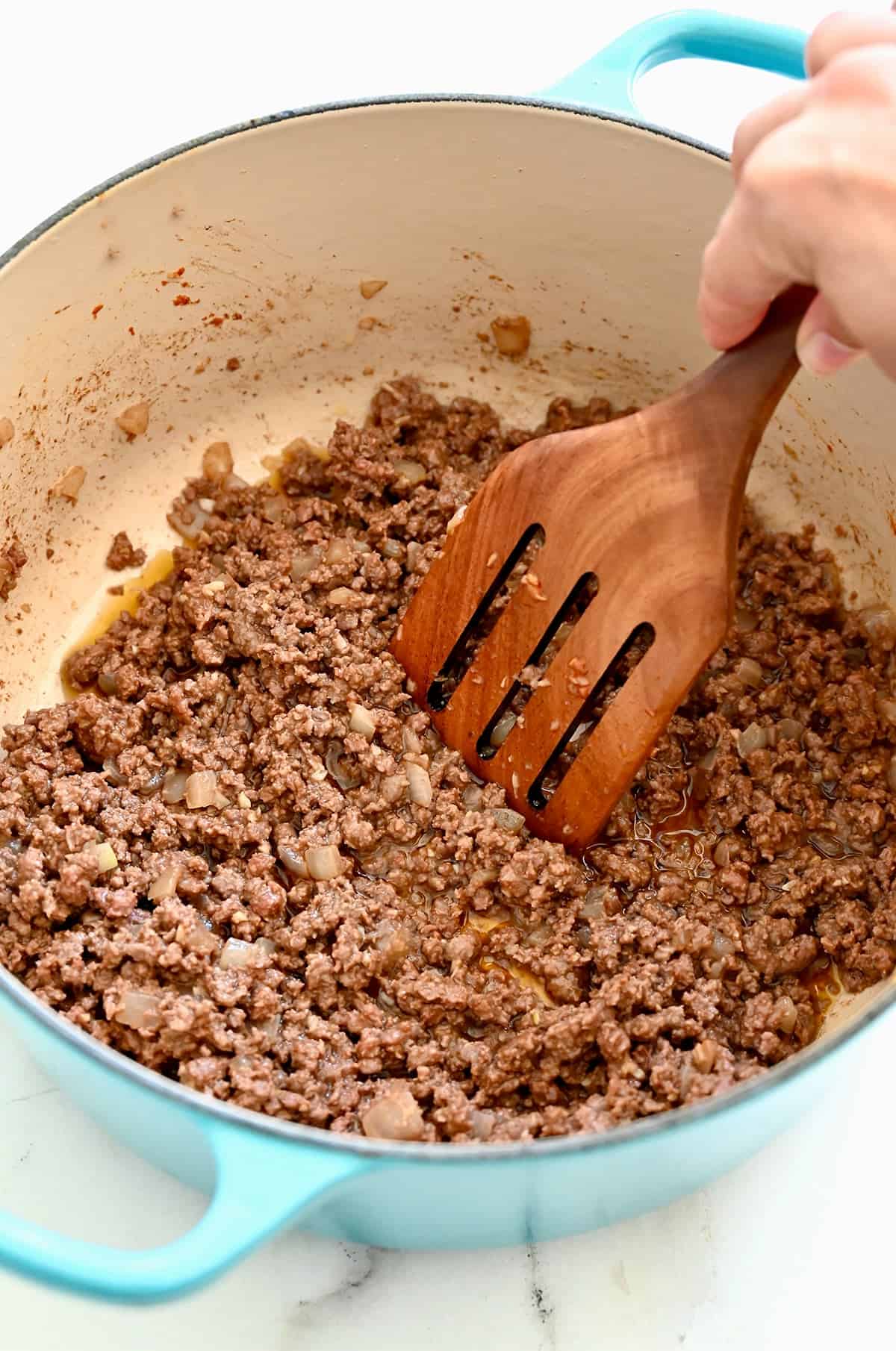 Browned ground beef and diced onions in a Dutch oven.
