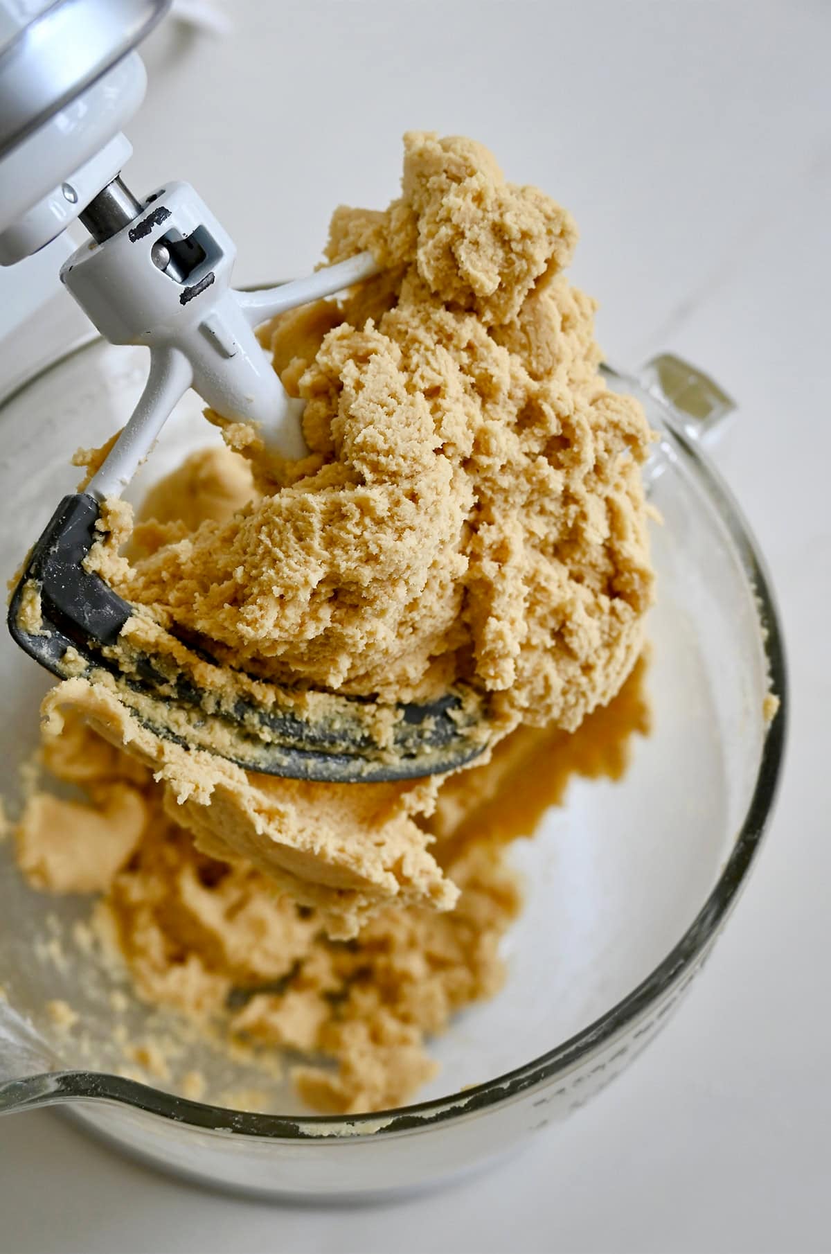 Slice-and-bake cookie dough in covering the paddle attachment of a stand mixer.