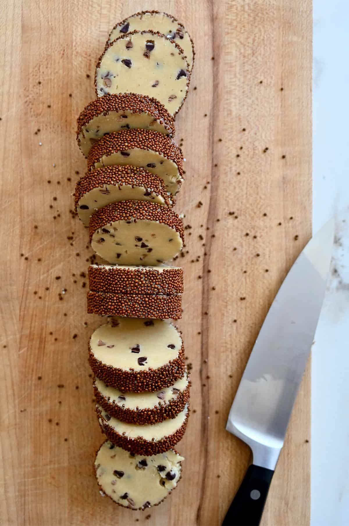 Sliced cookie rounds on a cutting board with a sharp knife.